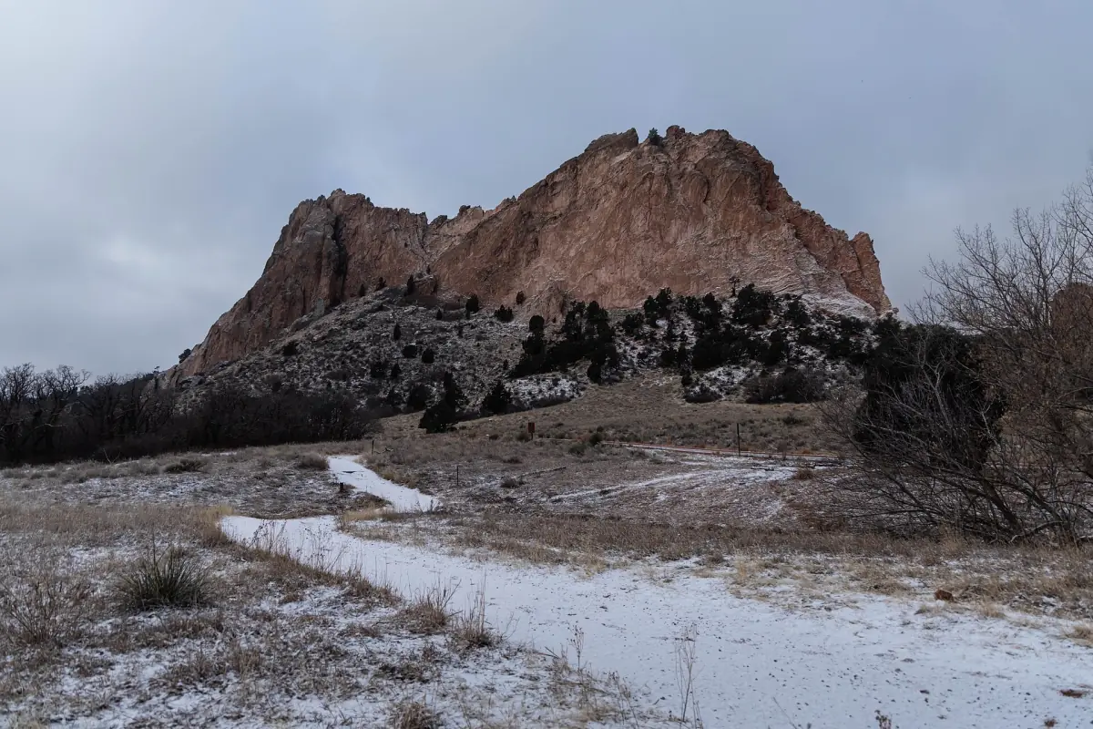 A snowy path leading toward a large rock formation in winter